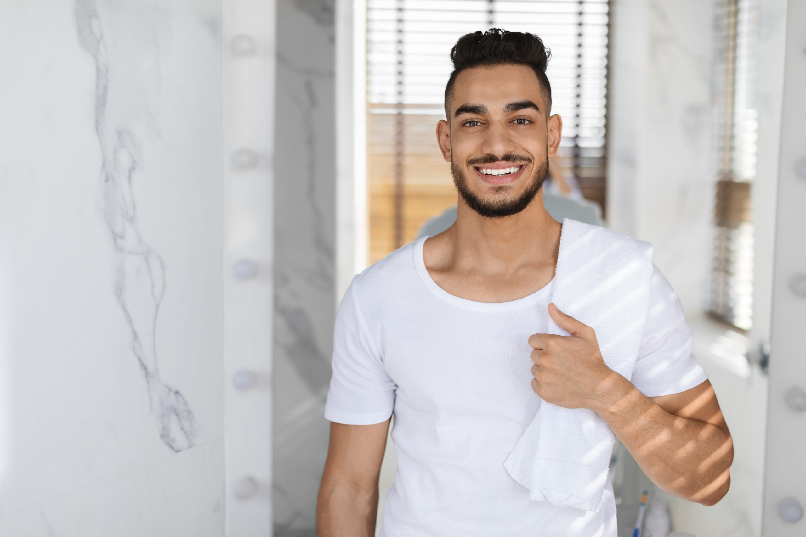 Handsome Young Arab Man With Towel On Shoulder Posing In Bathroom