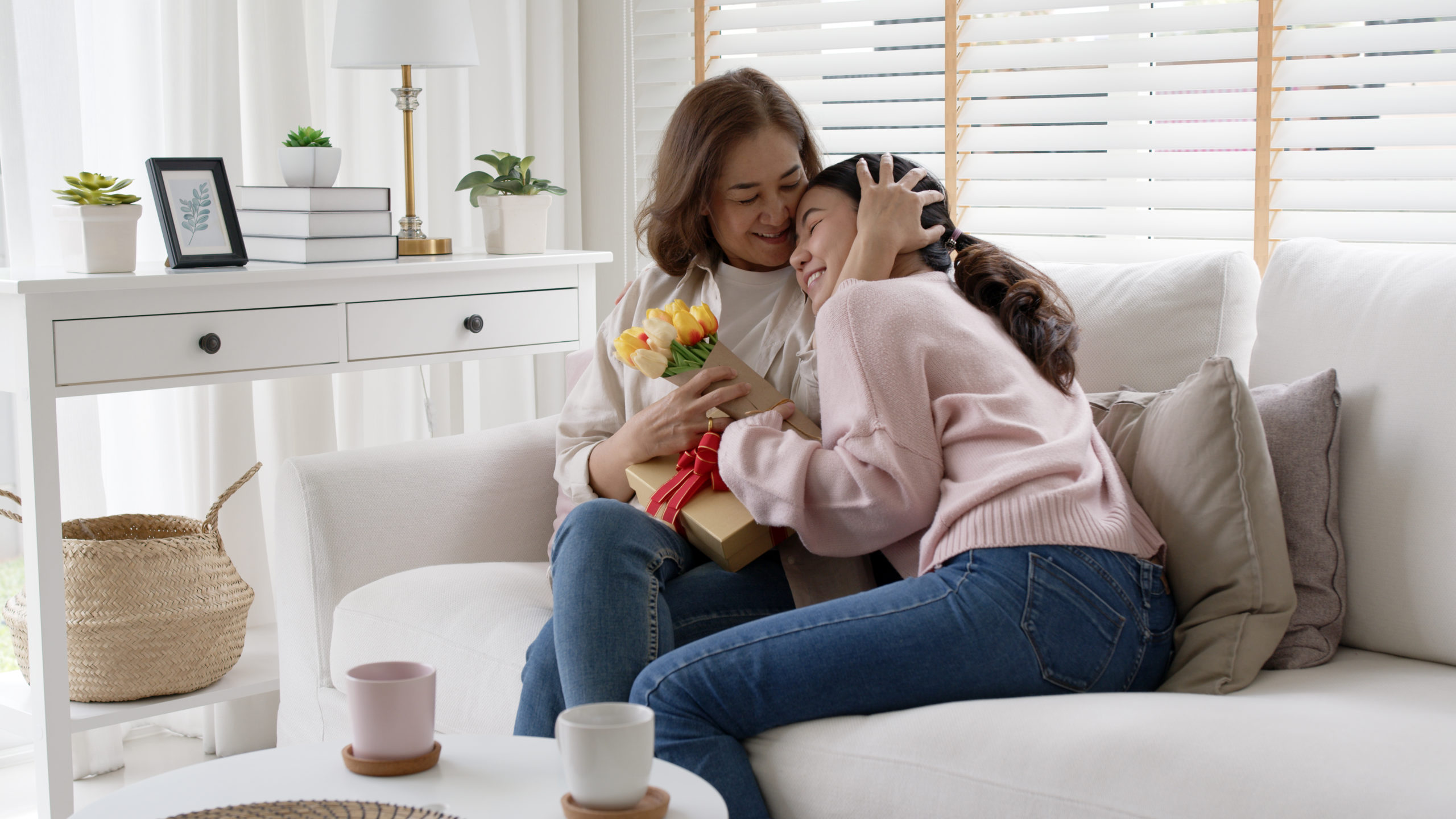 Attractive beautiful asian middle age mum sit with grown up daughter give gift box