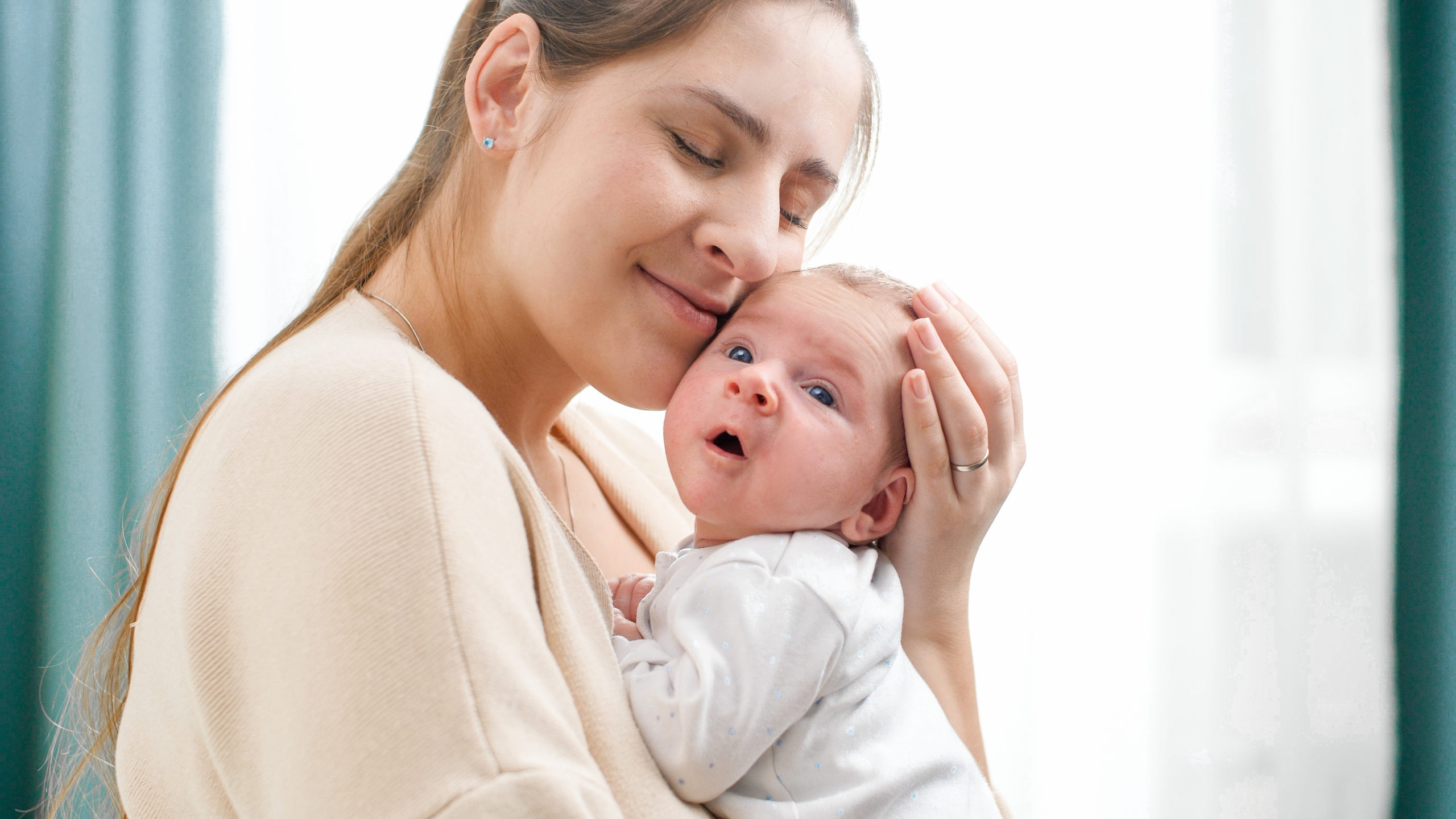 Closeup portrait of happy smiling mother holding and looking on her newborn baby boy. Concept of